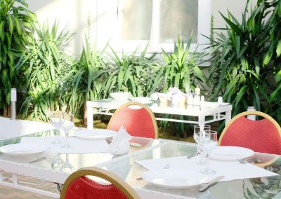 particolare di una tavola in vetro con apparecchiatura elegante e sedie rosse